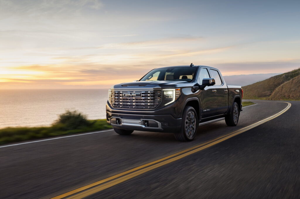 2026 GMC Sierra 1500 Denali driving on a coastal highway at sunset, featured in GMC Sierra 1500 Review