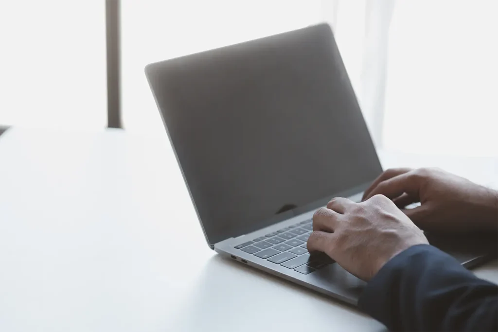 Person using a laptop to research invoice price lookup sources for accurate vehicle pricing data