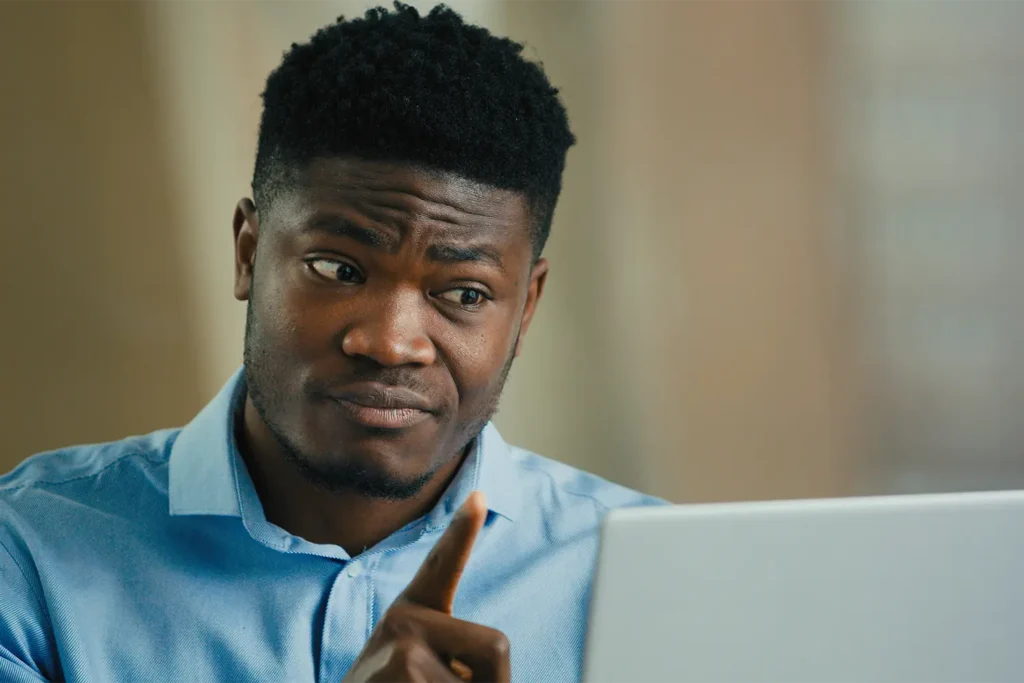 Man looking confused at laptop while researching invoice car price lookup information