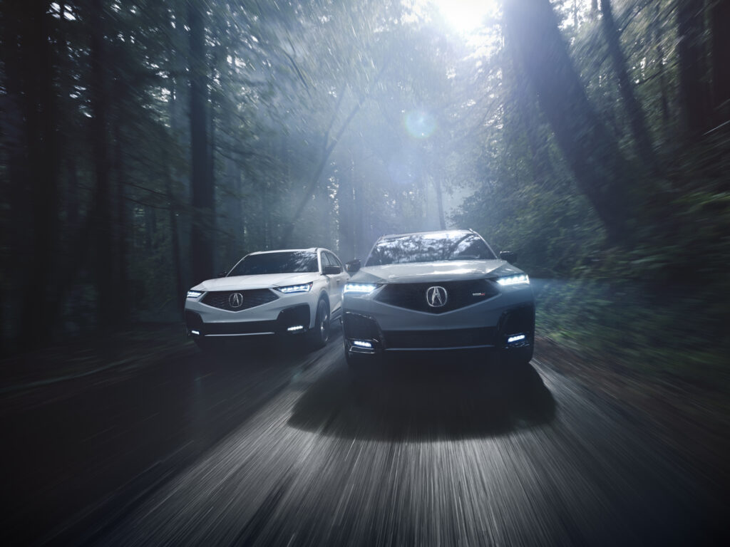 Acura MDX Review image of two 2026 Acura MDX SUVs driving on a forest road