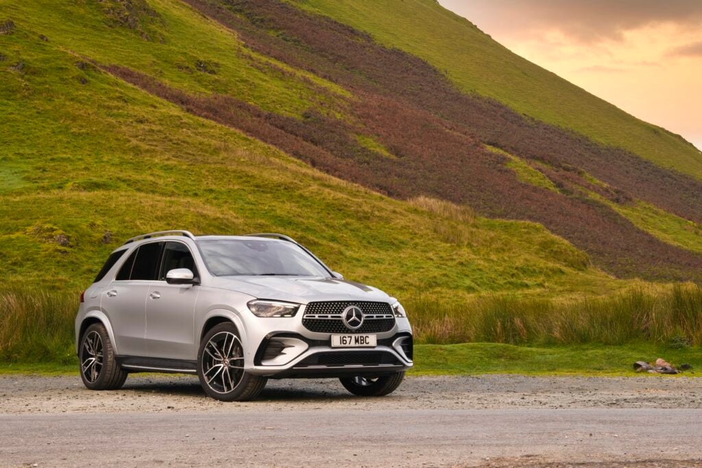 Silver Mercedes-Benz GLE luxury SUV parked in front of green hills and open countryside for a Mercedes-Benz GLE Review.