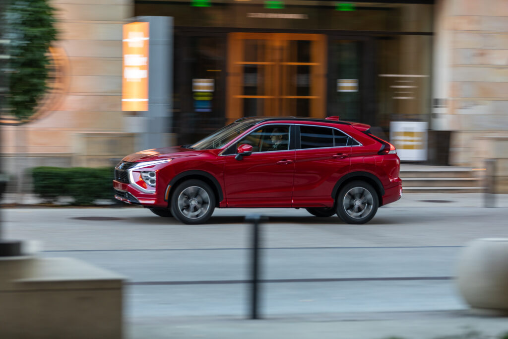Red Mitsubishi Eclipse Cross driving through a city street in side profile for a Mitsubishi Eclipse Cross Review.