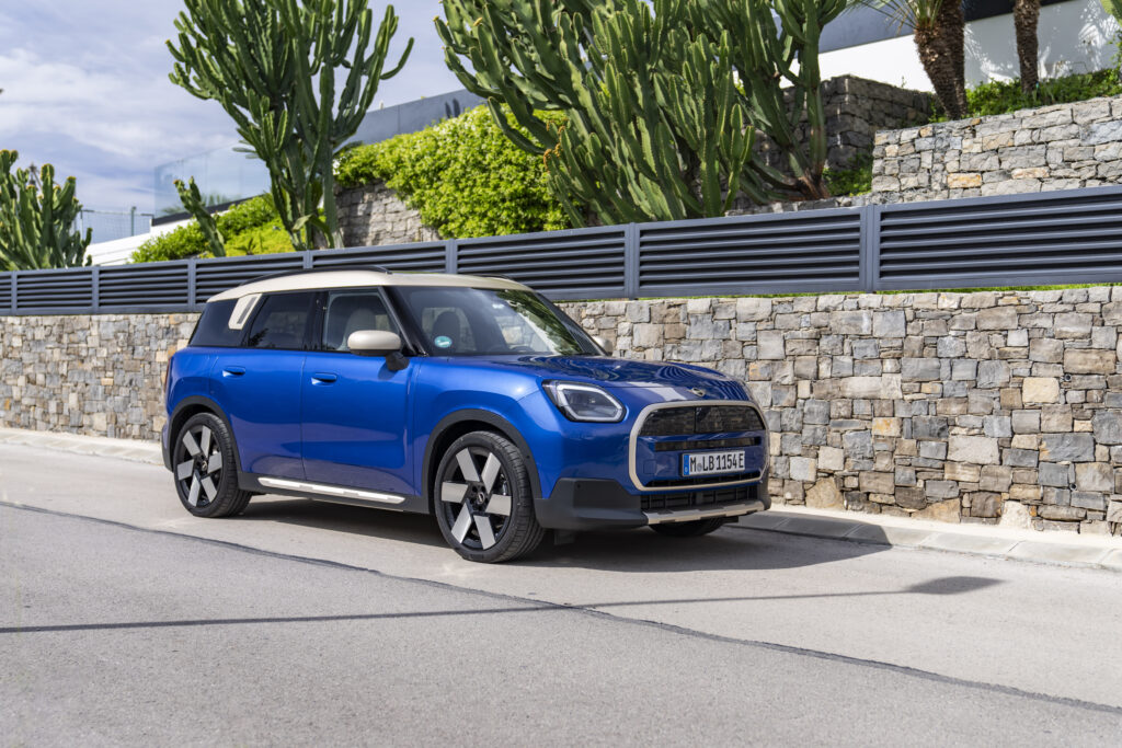 Blue MINI Countryman parked on a street beside a stone wall and tall cacti for a MINI Countryman Review.