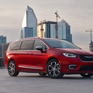 Red Chrysler Pacifica Pinnacle minivan parked on a rooftop with a city skyline, featured in our Chrysler Pacifica Review.