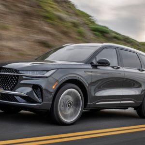 Black Lincoln Nautilus SUV driving on a paved road with a rocky hillside in the background for a Lincoln Nautilus Review.
