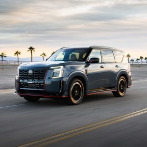 Gray Nissan Armada SUV driving on an open road with palm trees and mountains in the background for a Nissan Armada Review.