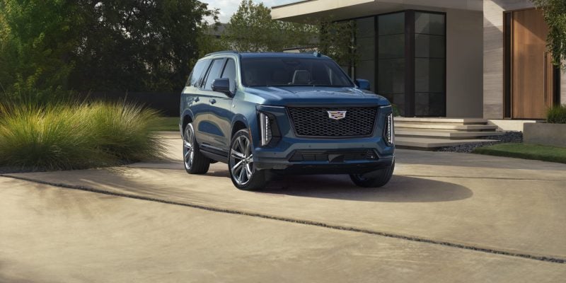 Blue Cadillac Escalade parked in a modern driveway, shown in our Cadillac Escalade Review.