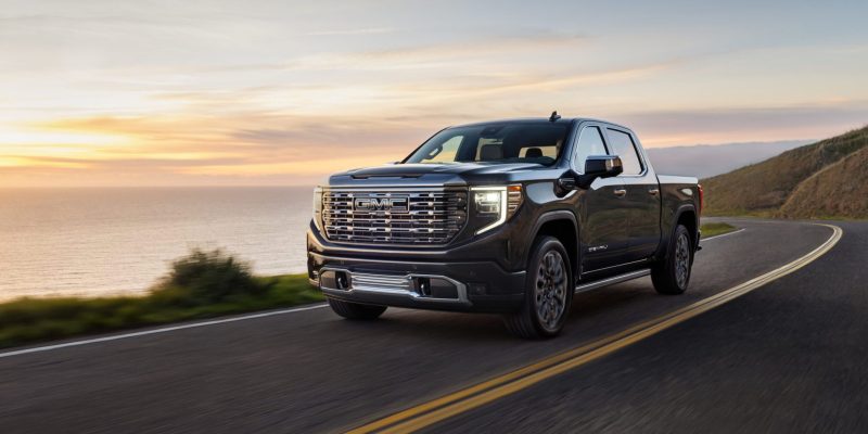2026 GMC Sierra 1500 Denali driving on a coastal highway at sunset, featured in GMC Sierra 1500 Review
