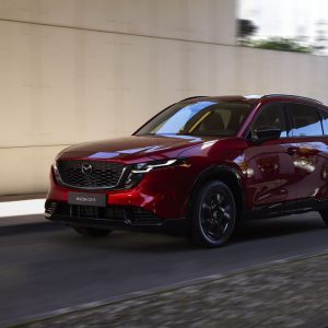 Mazda CX-5 Review image of a red 2026 Mazda CX-5 driving, front three-quarter exterior view