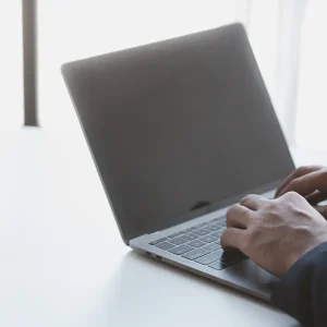 Person using a laptop to research invoice price lookup sources for accurate vehicle pricing data