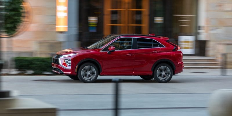 Red Mitsubishi Eclipse Cross driving through a city street in side profile for a Mitsubishi Eclipse Cross Review.