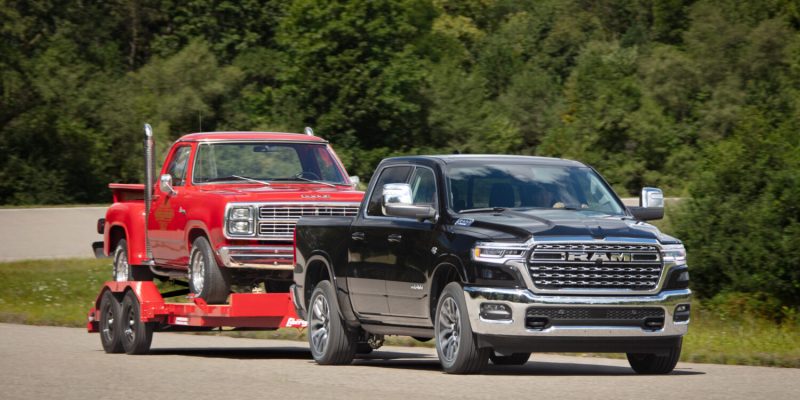 2026 Ram 1500 towing a classic red Dodge pickup on a trailer, featured in Ram 1500 Review