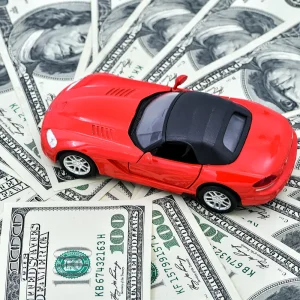 Red toy car on hundred dollar bills representing costly invoice car price lookup mistakes