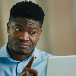 Man looking confused at laptop while researching invoice car price lookup information